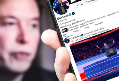 Poltava, Ukrayna - 21 Ocak 2025. Elon Musk Twitter profili sayfasında elinde akıllı telefonuyla yeni bir tweet var. Arka planda Elon Musk 'un odaksız bir portresi var..