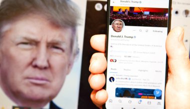 27 Nisan 2025. Ukrayna. Poltava. Donald Trump Twitter 'da. Cep telefonunda Donald Trump profili ve dizüstü bilgisayardaki Trump portresi..