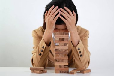 Klasik süitteki iş kadını kafasına dokunuyor ve oturuyor, tahta blok dominoları üzerine yüzüstü yatıyor. Yatırım Sigortası veya iş riski kontrol kavramı