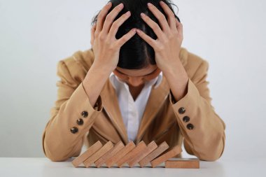 Klasik süitteki iş kadını kafasına dokunuyor ve oturuyor, tahta blok dominoları üzerine yüzüstü yatıyor. Yatırım Sigortası veya iş riski kontrol kavramı