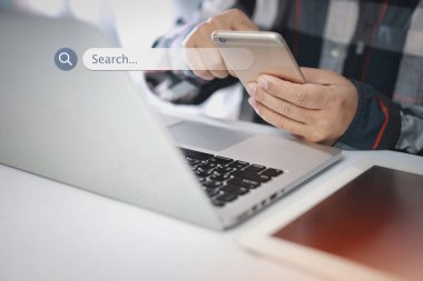 Akıllı erkek eller dizüstü bilgisayar klavyesi ve akıllı telefon araması kullanıyor, arama çubuğu konsolu ekranda etkileşimli internet verilerini tarıyor. Teknolojiyle yaşam tarzı