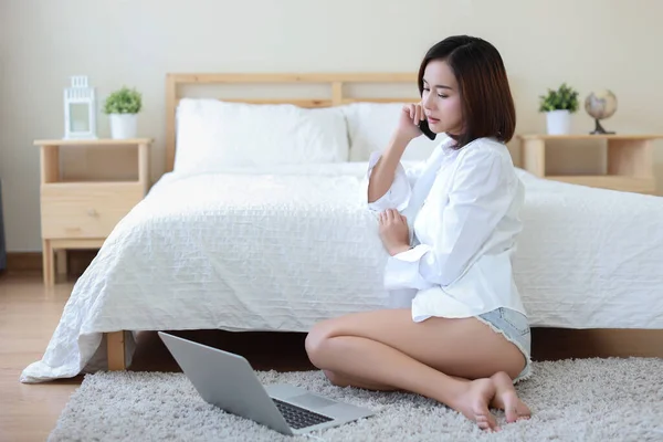 自宅でコンピュータやスマートフォンを使用している間 床の上に座ってカジュアルな幸せなアジアの女性 寝室の背景を持つ美しさのビジネス女性 ライフスタイル技術コンセプト — ストック写真