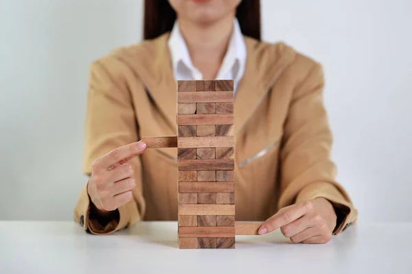 stock image Businesswoman hands in classic suite sitting and playing or controling wooden block dominoes on table from business risk, Investment Insurance or business risk control concept