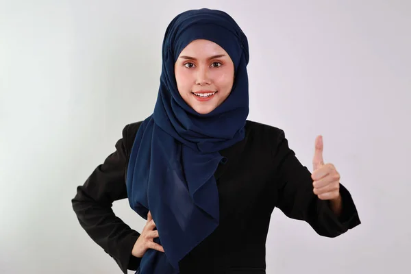 スタジオで自信を持って親指を立ててカメラを見ている間にムスリムドレス姿の幸せなスマートアジアのビジネス女性 孤立した白い背景の肖像画で美しい顔でヒジャーブ — ストック写真