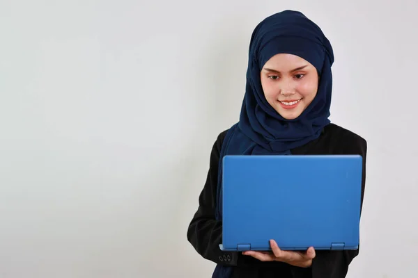 スタジオで自信を持ってパソコンを使い笑顔で立っているムスリムドレス姿の幸せなアジア系ビジネス女性 孤立した白い背景の肖像画で美しい顔でヒジャーブ — ストック写真
