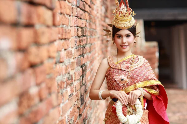 タイの赤い伝統衣装を着た若いファッションと美しいアジアの女性を笑顔でお楽しみください古代の仏教寺院で屋外に立ってジャスミンの花のガーランドアユタヤ 旅行のコンセプト — ストック写真