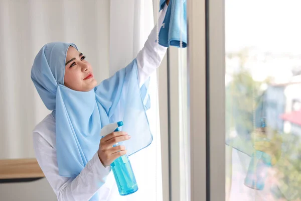 室内射精的年轻漂亮的亚裔穆斯林家庭主妇拿着清洁剂 洗窗玻璃 搬进新公寓后 带着快乐的情绪清洁卧室的可爱的画像女孩 — 图库照片
