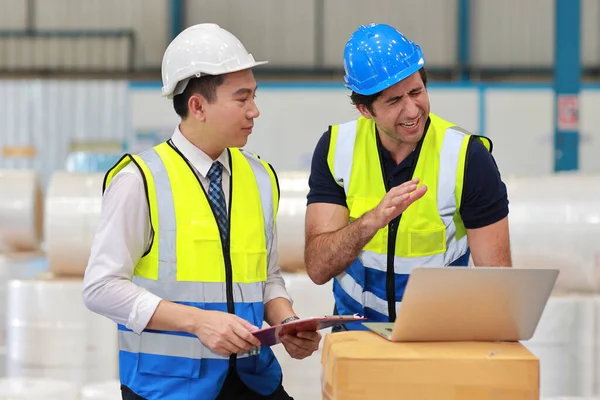 stock image Architect or engineering men and worker standing and checking large warehouse with tablet. Multiethnic two business manager controlling work at warehouse industry building. 