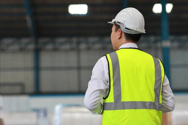 大規模な倉庫をチェックしながら アジアの建築家やエンジニアの男と労働者が立って何かを見て 倉庫ビルを背景に将来計画しているアジアのビジネスマネージャー — ストック写真