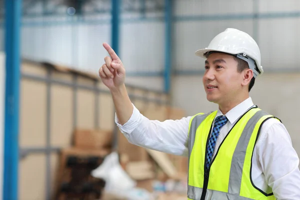 大規模な倉庫をチェックしながら アジアの建築家やエンジニアの男と労働者が立って何かを指す 倉庫ビルを背景に将来を見通すアジアのビジネスマネージャー — ストック写真