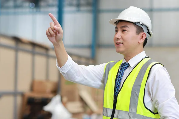 大規模な倉庫をチェックしながら アジアの建築家やエンジニアの男と労働者が立って何かを指す 倉庫ビルを背景に将来を見通すアジアのビジネスマネージャー — ストック写真