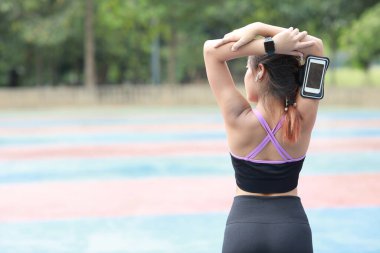 Spor giyim mağazasında sporcu kılığında genç, sağlıklı ve güzel Asyalı bir kadın egzersiz yapmak için dışarı çıkıyor. Aktif kız cep telefonuyla pazı egzersizi yapıyor. Spor ve yaşam tarzı kavramı