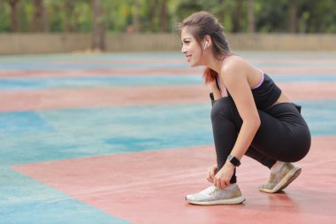 Spor giyimli güzel Asyalı kadın portresi açık havada koşuyor ince atletik bacaklarıyla. Sportif kız elleri ara verip ayakkabılarını bağlar. Antrenmandan sonra. Sağlıklı ve yaşam tarzı açık hava kavramı 