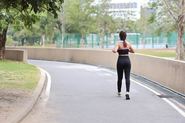 マラソントレーニングのためのスポーツウェアジョギング屋外でスポーティな若いアジアの女性の肖像画 緑の木の背景とコンクリートのパスの屋外に沿って運動ジョガーの女の子 スポーツコンセプト — ストック写真