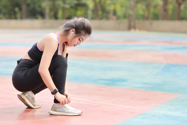 スリムな運動脚でスポーツウェアジョギング屋外での美しいアジアの女性の肖像画 スポーティーな女の子の手が休憩と靴を結ぶ ワークアウトの後 健康的でライフスタイルのアウトドアコンセプト — ストック写真