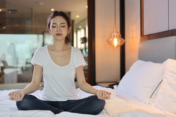 Asian woman wearing white sleepwear practicing mediate yoga. Lifestyle concept.