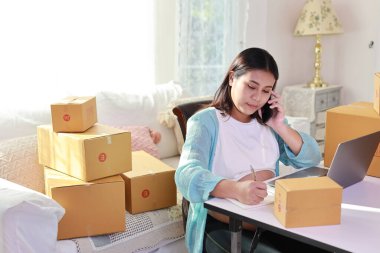 Çekici mutlu Asyalı hamile kadın oturuyor, cep telefonu kullanıyor ve tabletli müşterileri kontrol ediyor. Müstakbel anne hamilelik konsepti sırasında bebek doğurmaya hazırlanıyor ve çalışıyor..