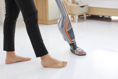 KOBİ ve E-ticaret paketi arka planında elektrikli süpürge kullanan aktif ev kadını bacakları. Siyah taytlı temizlikçi kız odasını süpürüyor. Kapalı alanda temizlik kavramı