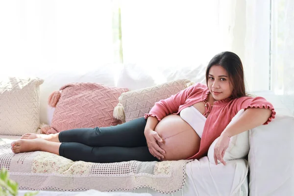 Ευτυχισμένη Χαμογελαστή Νεαρή Ασιάτισσα Έγκυος Γυναίκα Που Αναπαύεται Και Ξαπλώνει Εικόνα Αρχείου