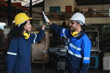 Mutlu gülümseyen takım çalışması teknisyeni veya koruyucu üniformalı işçi ağır sanayi imalat fabrikasında anlaşmanın başarıyla sonuçlanmasını kutluyor.