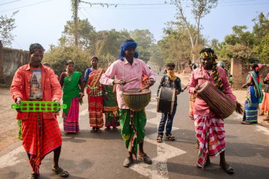 Birbhum, Westbengal, Hindistan - 14 Ocak 2024; Bir grup genç yerli insan müzik yapıyor ve yerel müzik enstrümanlarıyla yolda dans ediyorlar.