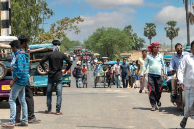 Birbhum, Batı Bengal, Hindistan - 19 Nisan 2021; Hindistan 'ın kırsal kesiminde yayaların otobüslere, toto ve otomobil arabalarının kavurucu yaz güneşinde sokaklara döküldüğü yoğun bir yolun resmi.