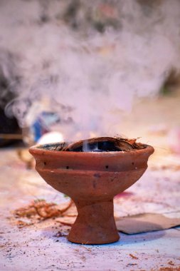 Aarti 'deki puja sırasında kullanılan Dhunuchi olarak bilinen Bengali tütsü yakma fırınının resmi, toprak malzemesinden yapılmış, tabanda yanan kömür tutmak için dizayn edilmiş, yavaş yanan hindistan cevizi kabuğunu tutuşturmak için, genellikle Hint tütsüsü ile birlikte kullanılır.