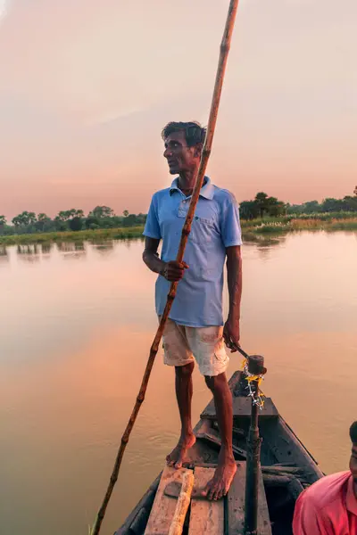 stock image Bardhaman, West Bengal, India - October 2, 2021; in the serene backdrop of rural Bengal, a village boatman carefully navigates a boat on the calm river. This imagery paints a vivid picture of simplicity