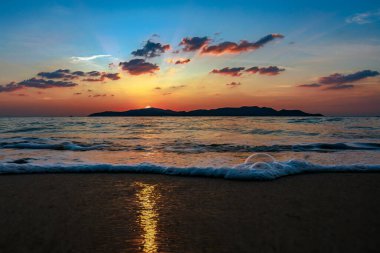 Sahilin gün batımında ön planda kumlu bir sahil ve deniz suyuyla çekilmiş fotoğrafı. Arka plan Khram Yai Adası. Sahilin adı Haad So, Chonburi Eyaleti, Sattahip Bölgesi..