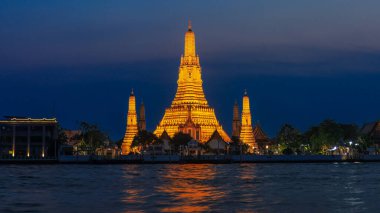 Wat Arun Ratchawararam Ratchawaramahawihan gün batımında Gece Işıkları. Ön planda Chao Phraya Nehri var. Bu, Bangkok, Tayland 'da tavsiye edilen bir turizm merkezidir..