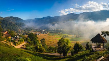 Tayland 'ın kuzeyinde Tayland' ın Nan Eyaleti 'ndeki bir vadinin ortasındaki küçük bir köyde yüksek dağları ve pirinç tarlalarını gören popüler bir turizm merkezi olan Sapan Köyü' nün havadan görünüşü..