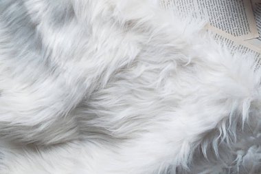 Krem renkli sahte kürk ve kitap sayfaları. Havadan düz atış.