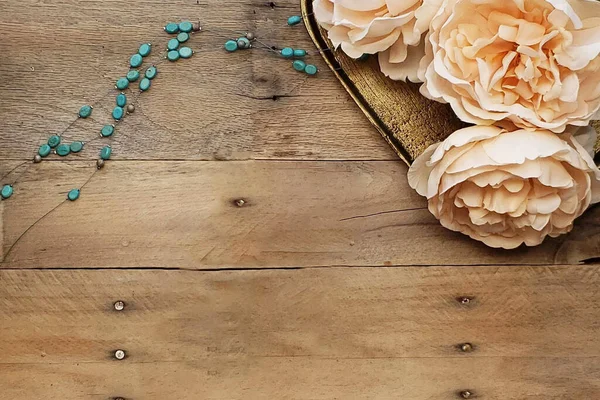A rustic aerial flat lay over a rustic barn wood background with peach peonies and turquoise stones. Country feel, rural, farmhouse, fashion.