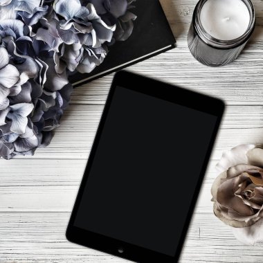 Tablet ipad ve beyaz arka planda çiçekler. düz yat