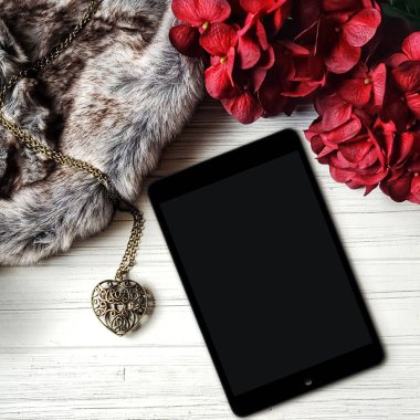 iPad ve kırmızı ortancalar ve sahte kürklü düz maket okuyun