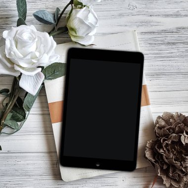 Boş beyaz ekranlı tablet ve bir buket gül..
