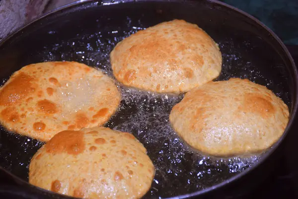 Kızartma tavasında chapati (poori), kızartma tavasında kızgın yağ koyu arka planda, mutfak konsepti, seçici odaklanma