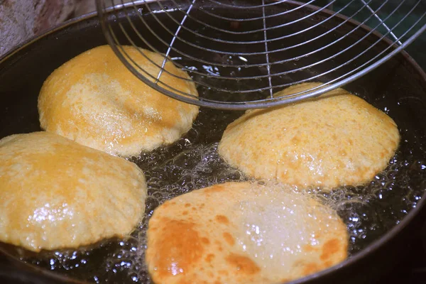 Kızartma tavasında kaşık ile kızartılmış chapati (poori), koyu arka planda kızgın tavada kaynar yağ, mutfak konsepti