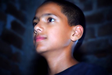 Karanlık stüdyoda neon ışıkla çekilen şık bir çocuğun portresi..