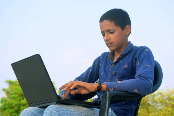 Laptop kullanan yakışıklı genç bir öğrenci. Neşeli çocuk internette çalışıyor. Teknoloji, iletişim, sosyal medya, gündüz