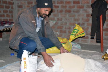 09-12-2021 Indore, Madhya Pradesh, Hindistan. Hintli çiftçi gübre elementlerini evde gübreye karıştırıyor. seçici odak