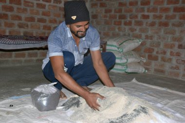 09-12-2021 Indore, Madhya Pradesh, Hindistan. Hintli çiftçi gübre elementlerini evde gübreye karıştırıyor. seçici odak