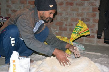 09-12-2021 Indore, Madhya Pradesh, Hindistan. Hintli çiftçi gübre elementlerini evde gübreye karıştırıyor. seçici odak