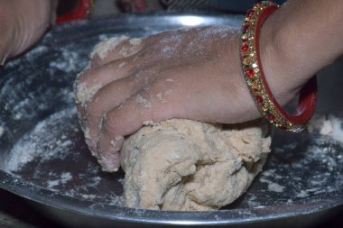 Hintli kadın hamuru teslim ediyor. Çelik tabakta hamur yoğuruyor, bilezik takıyor.