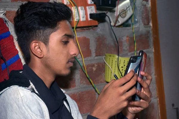 Індійський Підліток Використовує Два Мобільні Телефони Одночасно Вдома Цегляна Стіна — стокове фото