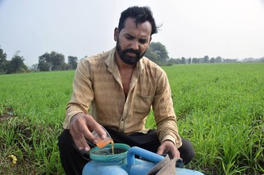 Bir çiftçi konteynıra ot ilacı ve kimyasal dolduruyor.