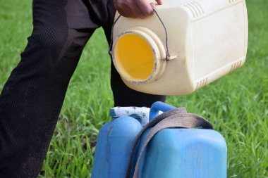 Yeşil tarladaki konteynıra bitki öldürücü ve kimyasal döken bir çiftçi konteynırdan köpük çıkıyor.