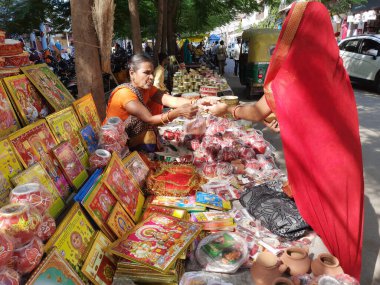 21 Ekim 2021 Dewas, Madhya Pradesh, Hindistan. Hintli bir kadın sokak pazarında toprak tencere ve elek satıyor.