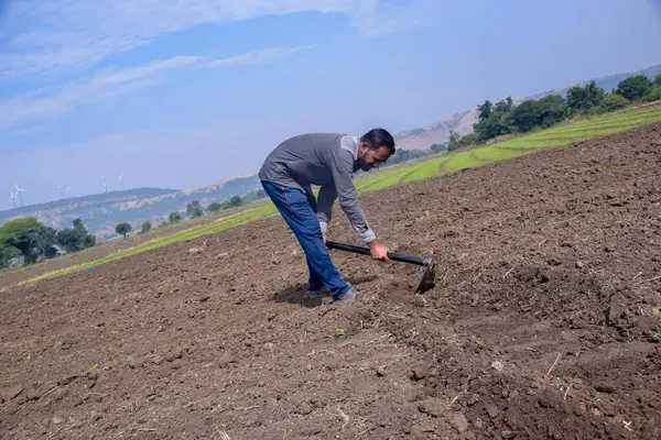 Hintli çiftçi tarlasını kazıyor bir kürek, çiftlik ve gökyüzü arka planıyla