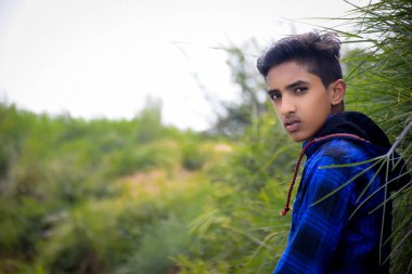 Mavi elbiseli Hintli manken çocuk, yeşillik arka planda..